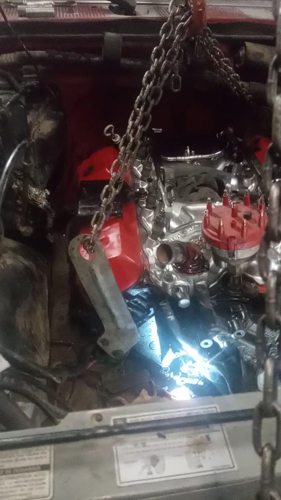 Engine lifted on a hoist chain above an open engine bay during a rebuild at A2Z Auto Repair